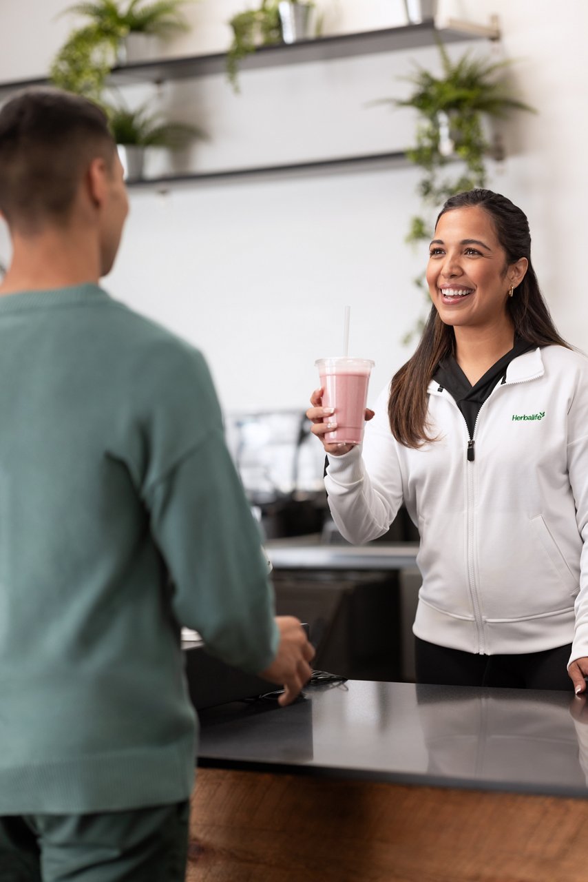 Woman about to hand over a shake to a friend Man receiving a shake from a friend.