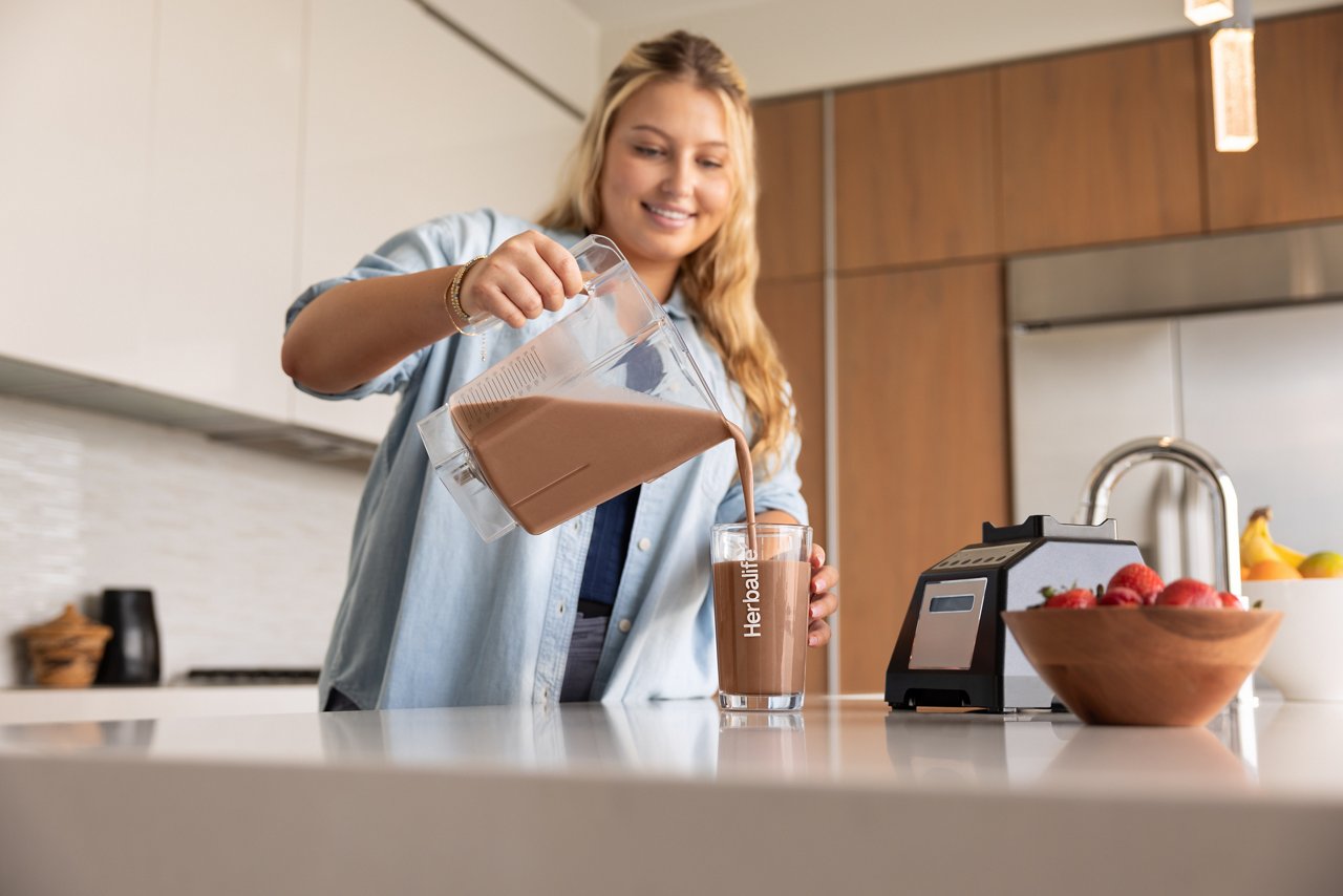 Woman smiles before enjoying an Herbalife Formula 1 meal replacement shake in her home. Woman smiles before enjoying an Herbalife Formula 1 meal replacement shake in her home.