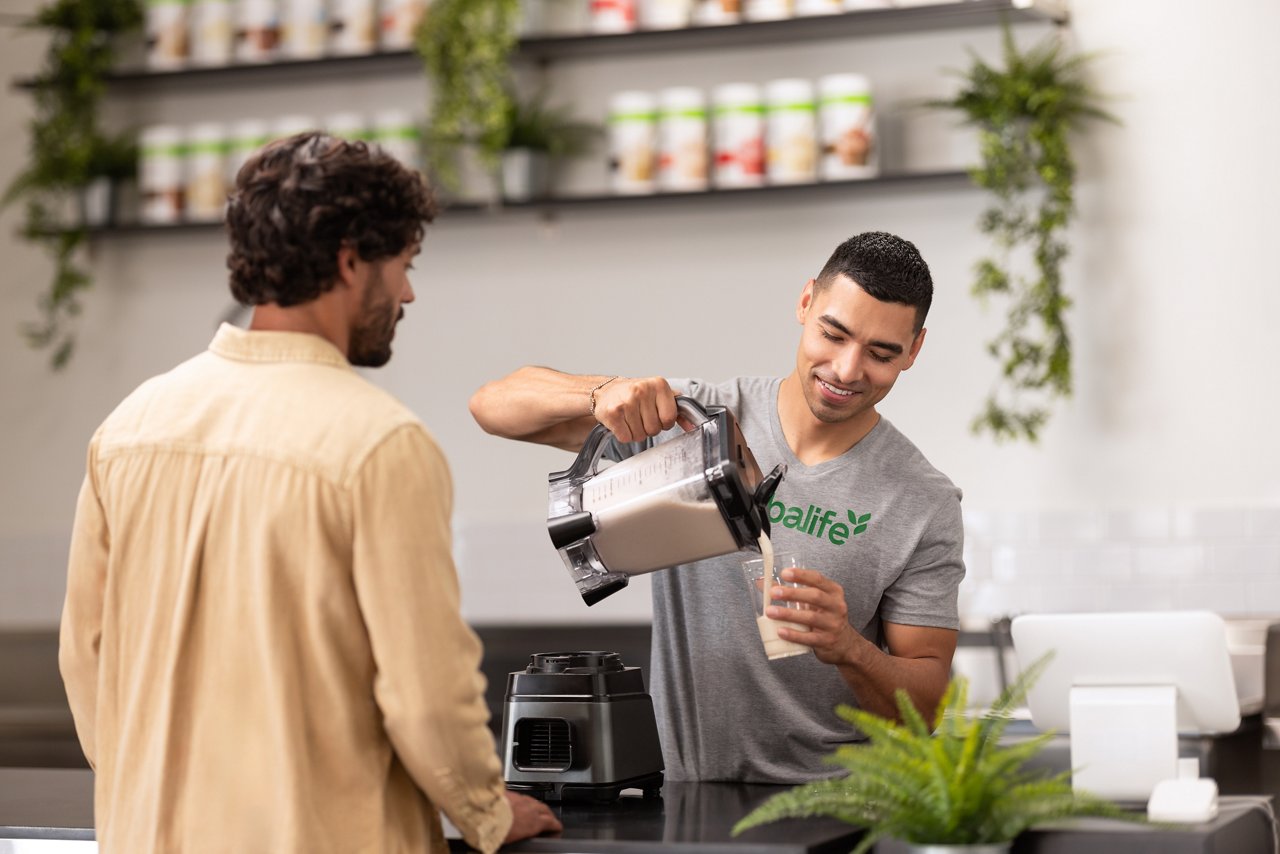 How do Herbalife product get sold Man pouring a shake for another man.