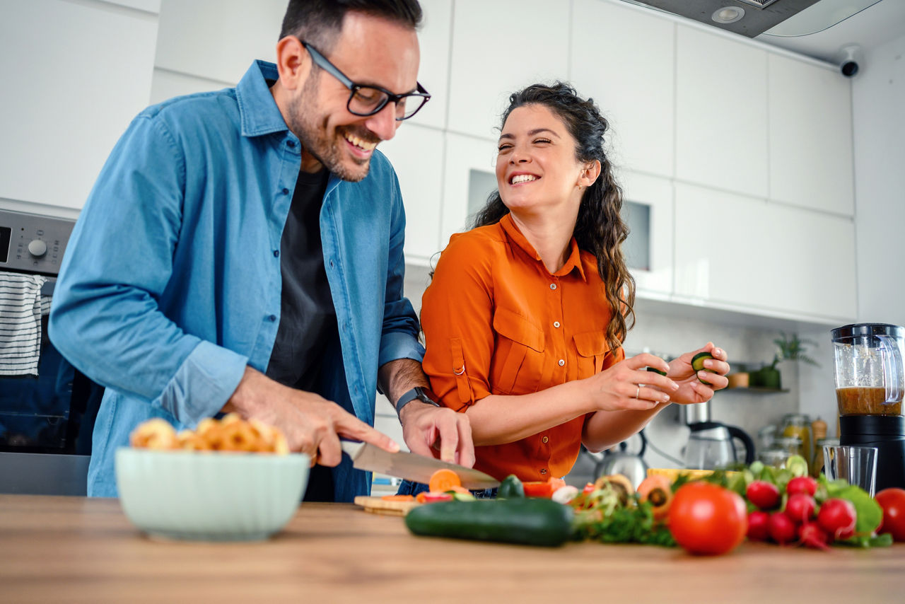 Loving couple preparing salad in a kitchen.